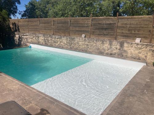 - une piscine avec un mur en pierre et de l'eau bleue dans l'établissement Mas climatisé avec Piscine à 10 minutes de Montpellier et des plages, à Lavérune