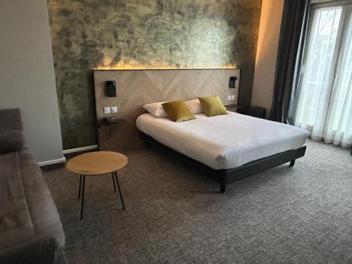 a bedroom with a bed and a table and a couch at Brit Hotel Privilège Le Royal - Centre Gare in Troyes