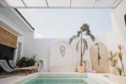 a pool in a white room with palm trees at Gisela Villa With Private Pool in Buleleng