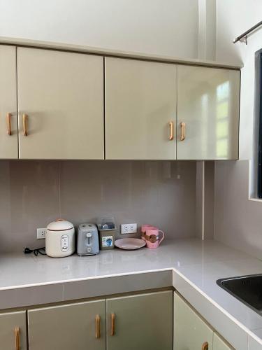 a kitchen with white cabinets and appliances on the counter at Riz Place Homestay - Bunk Bed x Air-conditioned in Bacnotan