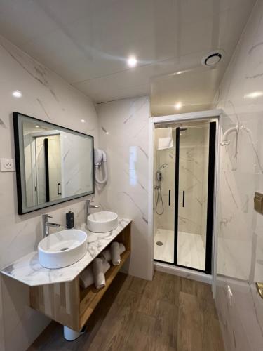 a white bathroom with two sinks and a shower at Brit Hotel Privil&egrave;ge Le Royal - Centre Gare in Troyes
