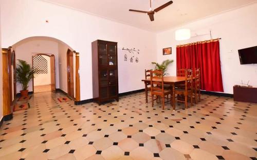 a dining room with a table and chairs and a red curtain at VILLA MARINAA 6 Rooms property in Puducherry