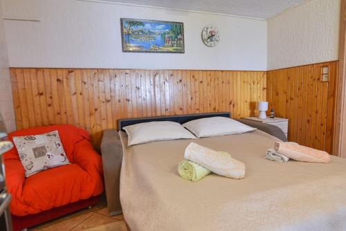 a bedroom with a bed and an orange chair at Apartment Brezina - Lovran - Liganj in Lovran