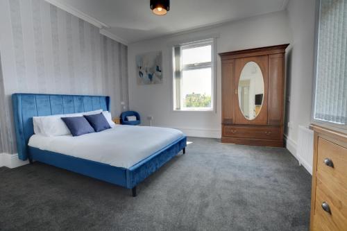 a bedroom with a blue bed and a mirror at Winwood House in Goole