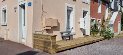 a bench sitting on a wooden deck next to a building at La Chaloupe in Saint-Aubin-sur-Mer