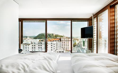 a bedroom with a large bed and a large window at Hotel Daniel Graz - Smart Luxury Near City Centre in Graz