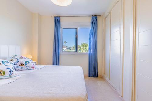 - une chambre avec un lit doté de rideaux bleus et d'une fenêtre dans l'établissement El Rinconcito, à Torre de Benagalbón