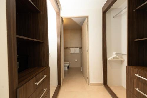a hallway of a bathroom with a toilet and a television at Ocean Breeze, Cancun Sanctuary - HiveNB in Cancún