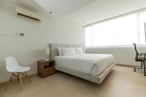 a white bedroom with a bed and a chair at Ocean Breeze, Cancun Sanctuary - HiveNB in Cancún