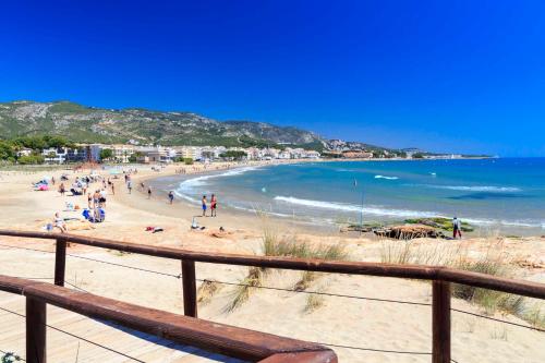 a beach with people on the sand and the ocean at APCOSTAS Cala Gonzalez in Alcossebre