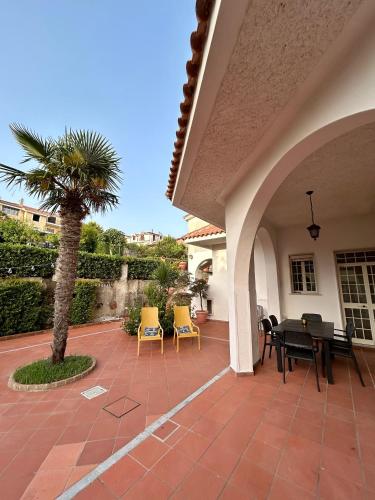 a patio with a table and chairs and a palm tree at Case Vacanze Torre Petrosa in Villammare
