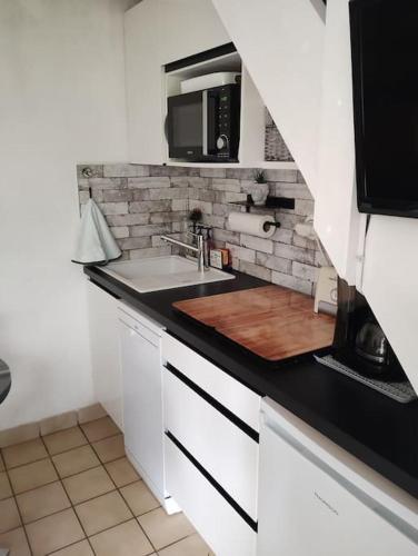 une cuisine avec un évier et un micro-ondes dans l'établissement Cottage à Cabourg, à Cabourg