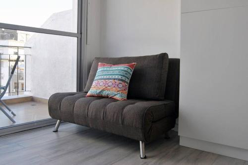 a brown chair with a colorful pillow on it in a room at Luminoso Estudio en Palermo, Las cañitas in Buenos Aires
