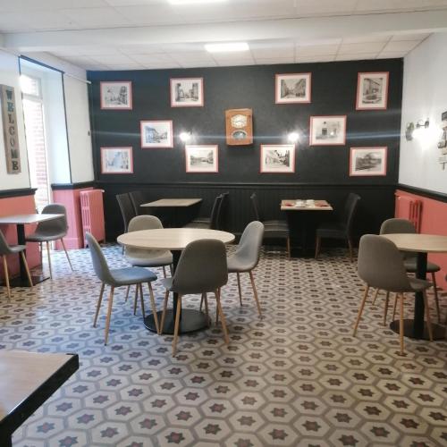 a waiting room with tables and chairs and pictures on the wall at Hotel Le Normandy in Beaumont-de-Lomagne