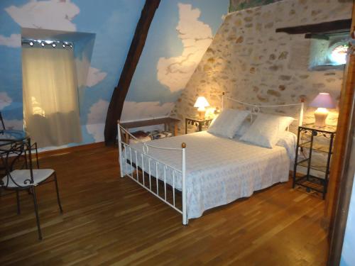 a bedroom with a white bed and a stone wall at Les 7 Lucarnes in Latouille-Lentillac