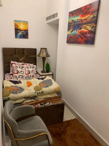 a bedroom with a bed and a chair and a painting at Frank spaces in Abu Dhabi