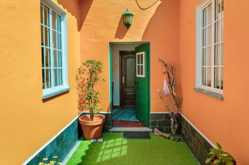 an orange house with a green door and a plant at Casa dos Castanheiros Angra do Heroismo in Terra Chã