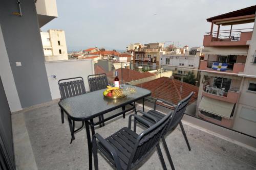 a table with chairs and a bottle of wine on a balcony at Mavili Luxury Apartments in Kavala