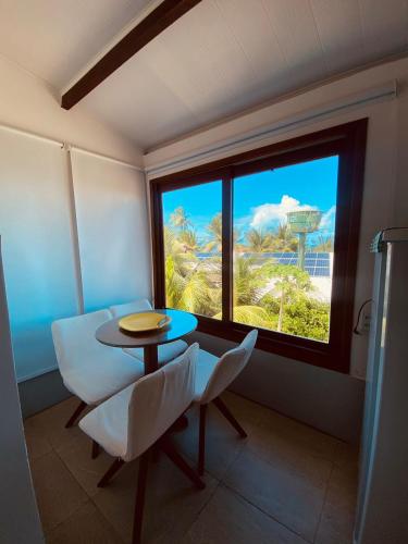 a room with a table and chairs and a window at Pontal dos Sonhos- Chalés Praia do Farol in Coruripe
