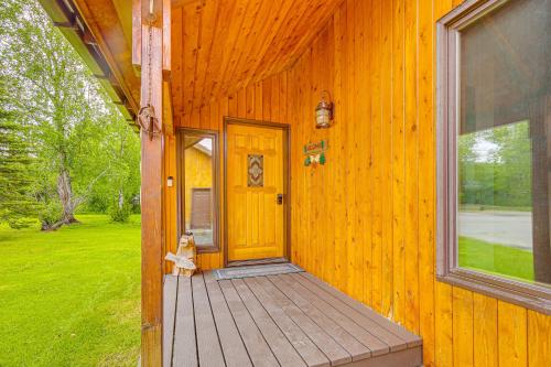 a front door of a wooden house with a cat sitting on the porch at Beautiful Wasilla Home Rental with Deck and Gas Grill! in Wasilla