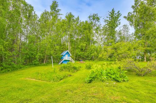 a small blue house in the middle of a field at Beautiful Wasilla Home Rental with Deck and Gas Grill! in Wasilla