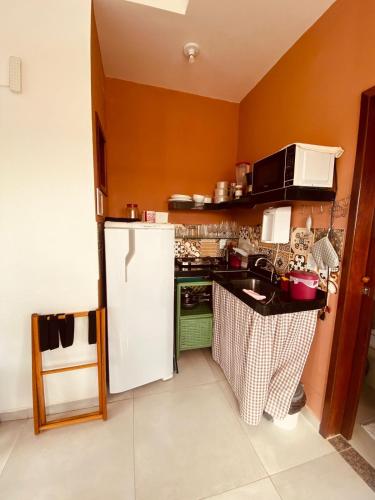 a kitchen with a white refrigerator and a sink at Pontal dos Sonhos- Chalés Praia do Farol in Coruripe