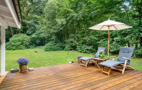 a wooden deck with two chairs and an umbrella at Nice Home In Frederiksværk With Wifi in Frederiksværk