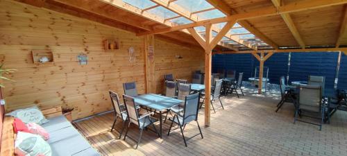 a patio with tables and chairs in a wooden building at Tavi Panzió in Dunapataj