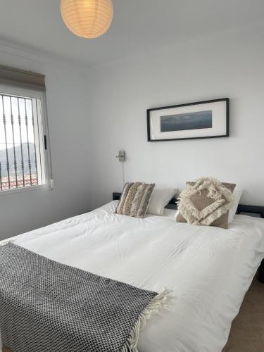 a white bed in a white room with a window at casita las Perlas in Cómpeta