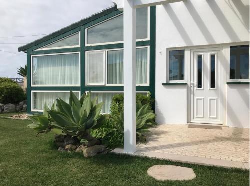 a white house with a green and white door at Praia da Areia Branca, Lourinhã - Vila Mar Casal dos Patos in Praia da Areia Branca