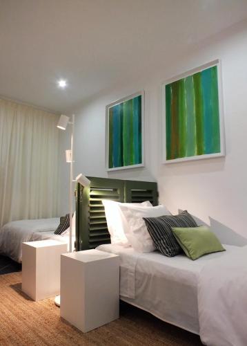 a bedroom with two beds with green paintings on the wall at Praia da Areia Branca, Lourinhã - Vila Mar Casal dos Patos in Praia da Areia Branca
