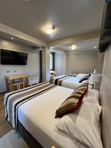 a hotel room with two beds and a flat screen tv at CASA CRISTOBAL Centenario in Cusco