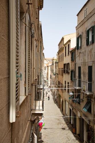 an alley with buildings and a person walking down the street at Honoré de Balzac in Alghero