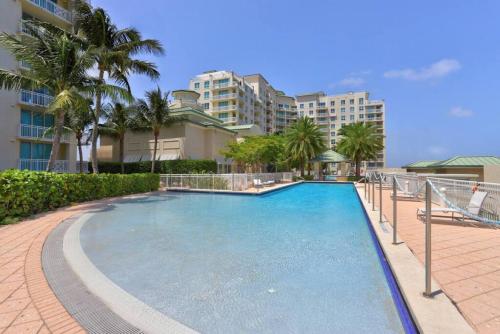 a large swimming pool with palm trees and buildings at 1 BR King- Rooftop Pool close to beach Casa Costa in Boynton Beach
