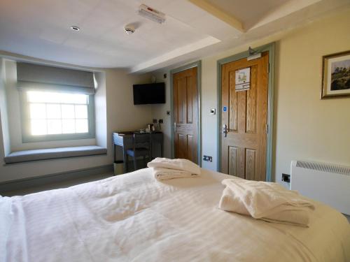 a bedroom with a white bed with a window and a desk at The Fox in Chipping Norton