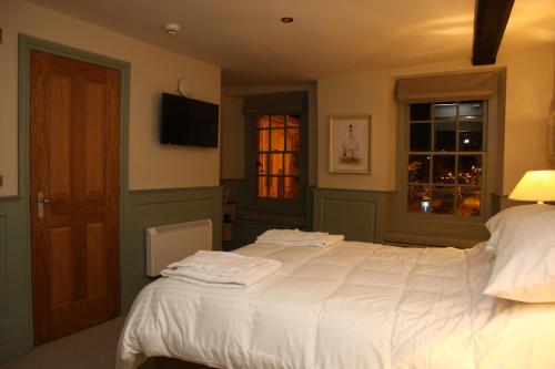 a bedroom with a bed with white sheets and a window at The Fox in Chipping Norton