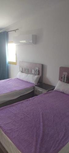 zwei Betten in einem Zimmer mit lila Decken in der Unterkunft Serene Escape Villa Ideal for family time and perfect for North Coast getaways in Dawwār Abū Maḩrūs