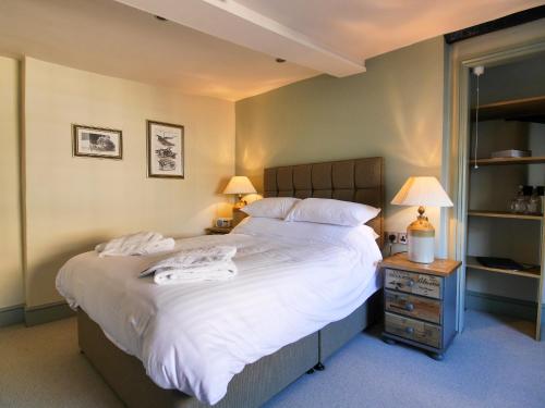 a bedroom with a large bed with white sheets and two lamps at The Fox in Chipping Norton