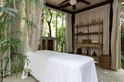 een slaapkamer met een wit bed in een kamer met bomen bij Arthouse Tulum Iconic Apartment Beach Club Access in Tulum