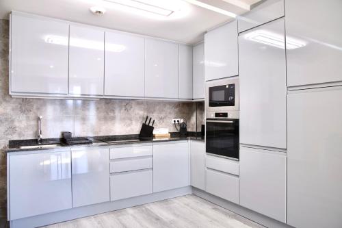 a white kitchen with white cabinets and appliances at Rosalia Park by Lugo Collection in Lugo
