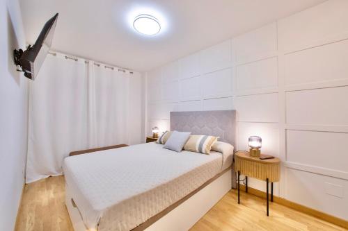 a white bedroom with a bed and a television at Rosalia Park by Lugo Collection in Lugo