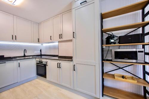 a kitchen with white cabinets and black appliances at Rosalia Park by Lugo Collection in Lugo
