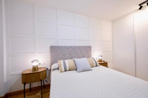 a white bedroom with a large bed and two tables at Rosalia Park by Lugo Collection in Lugo