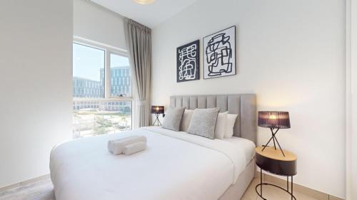 a white bedroom with a large white bed and a window at Vacationer Holiday Homes I Modern 1 Bedroom I Peaceful Location I Near Dubai Hills Mall & Park in Dubai