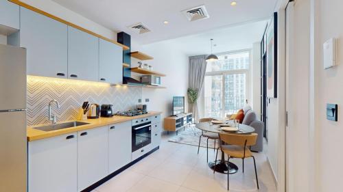 a kitchen with white cabinets and a table and a dining room at Vacationer Holiday Homes I Modern 1 Bedroom I Peaceful Location I Near Dubai Hills Mall & Park in Dubai