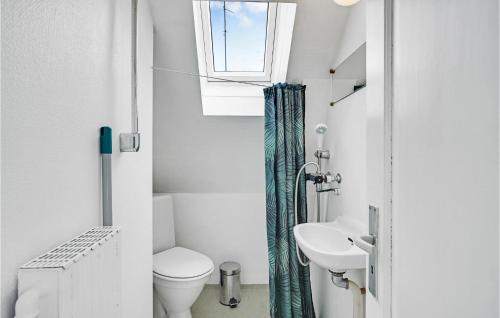 a bathroom with a toilet and a sink and a window at 2 Bedroom Cozy Apartment In Svendborg in Svendborg