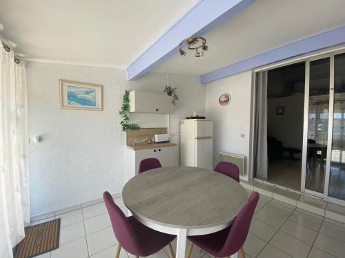 une cuisine et une salle à manger avec une table et des chaises violettes dans l'établissement Charmant T2 avec Terrasse, Clim, Parking et Wifi - FR-1-503-155, à Balaruc-les-Bains