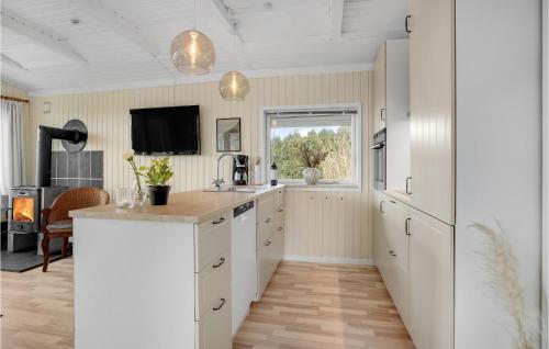 a kitchen with white cabinets and a tv on the wall at 3 Bedroom Pet Friendly Home In Bogense in Bogense