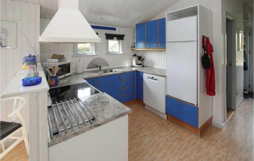 a kitchen with blue cabinets and a white refrigerator at 2 Bedroom Lovely Home In Samsø in Onsbjerg