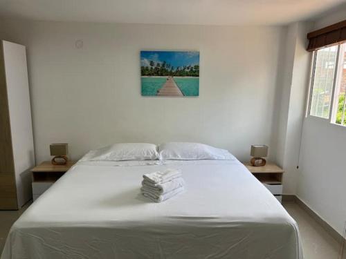 a bedroom with a large white bed with books on it at Hotel Orduz Centro Histórico de Cali in Cali